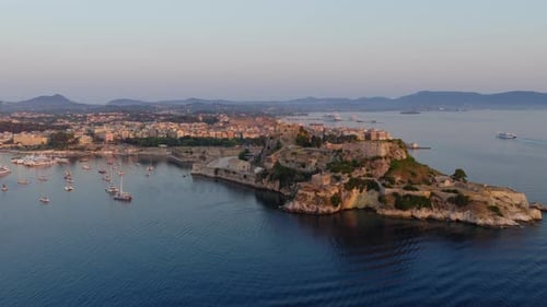 Lumière du lever du soleil sur la forteresse de Corfou avec une mer calme, suivi aérien à gauche