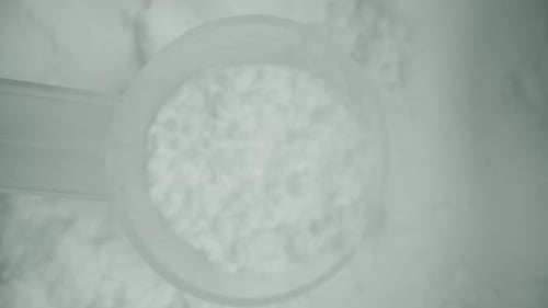 A measuring spoon from the jar of white powder. Sports supplement. Dolly macro zoom.