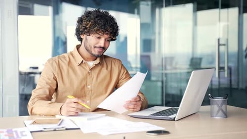Busy young manager preparing for presentation while sitting at the desk at workplace in modern