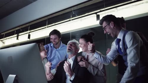 Eine Gruppe von Geschäftsleuten mit Computer in einem Büro, die Begeisterung ausdrücken