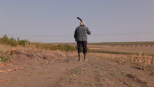 Steadfast in Farming Senior Man Walking with Shovel Back View and Tracking Shot