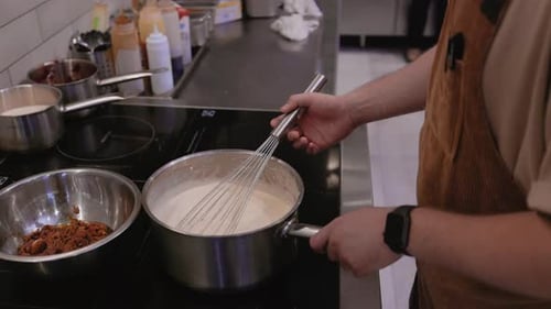 Chef Stirring Sauce on Stove in Commercial Kitchen