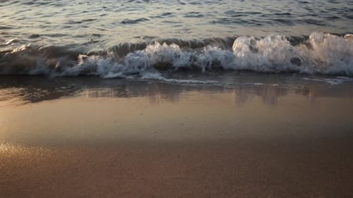 Waves rolling on sandy beach at the sunset, front view