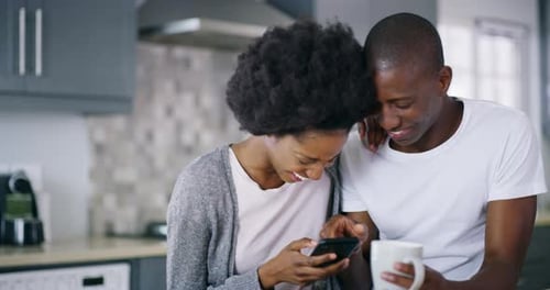 Affectionate Couple Using Mobile Phone in Kitchen