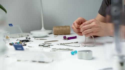 Adult Crafting Silver Jewelry at a Bright White Table