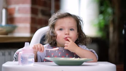 Adorable Child Eats Cheerfully in High Chair