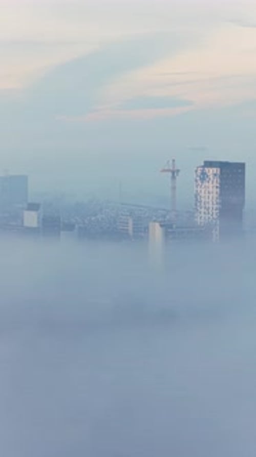 Aerial view of the Stevenskerk rising above Nijmegen during a foggy sunrise, with light mist