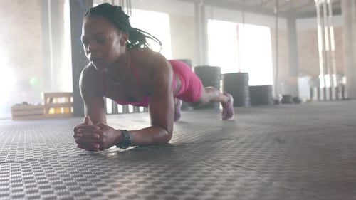 Planking on gym floor, woman in sportswear focusing on core strength workout, copy space