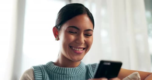 Young Woman Smiling Looking at Phone Indoors