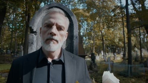 Portrait of Solemn Man in front of Old Stone Grave in Cemetery
