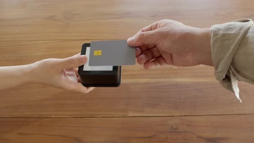 Close-up hands using mobile card reader terminal for contactless payment by tapping credit card