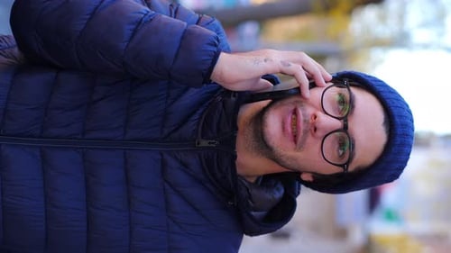 Cute man at the phone responding cheerfully: talking in the street