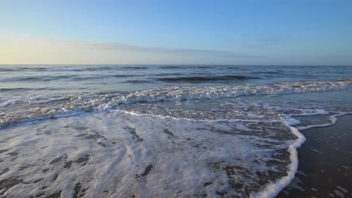 Waves crashing and moving up on beach shore in the morning. Ocean water waves breaking on beach shor