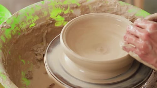 Une potière travaille sur un tour de potier et fabrique un pot en céramique en argile dans un atelier de poterie