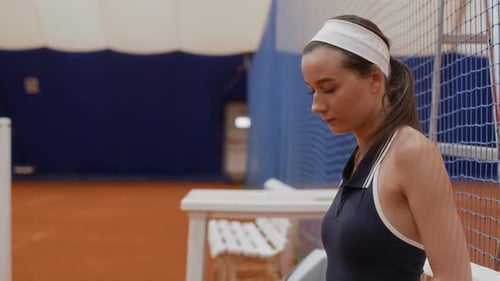 Young Female Tennis Player in Sportswear Adjusting Headband on Court
