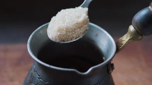 Pouring Sugar Into Coffee Cezve with Teaspoon Close Up