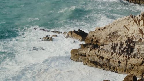 Aerial View of Ocean Water with Waves and Rocky Coastline at Sunny Summer Day