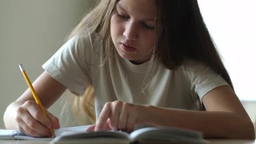 Teenage Girl Doing Homework Writing in Notebook