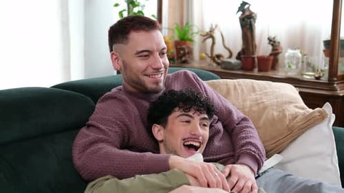 Affectionate gay couple cuddling watching television
