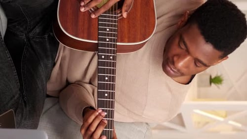 Young Adult Playing Guitar Indoors During Daytime