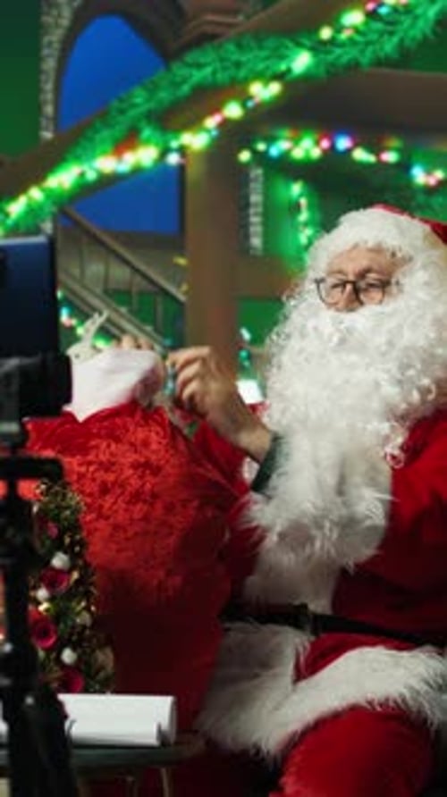 Vertical Video Santa Claus Filming with Phone on Tripod Showing Gifts to Children