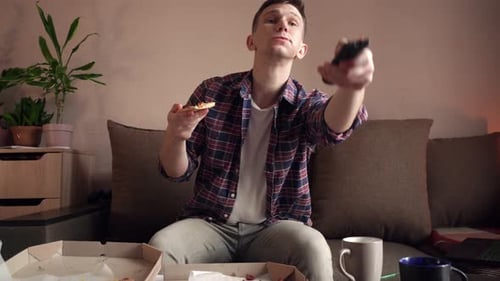 Man Eating Pizza and Watching TV at Home