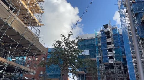 Sitio de construcción con andamios y edificios nuevos bajo un cielo despejado en Southampton. Un árbol está en pie