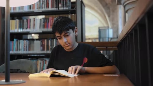 Junge, der ein Buch liest, blättert um
