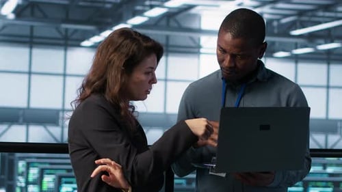 Developers in Data Center Workspace Coding on Laptop Analyzing Metrics