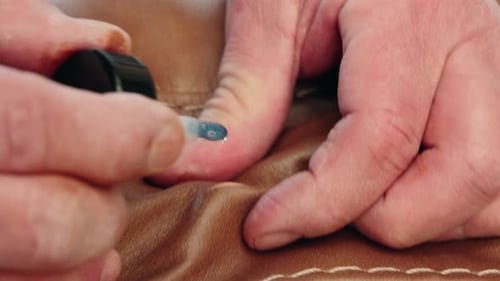 Static Closeup of Hands Sealing Cut in Brown Leather Sofa With Adhesive