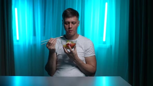 Young Adult Eating Salad with Chopsticks at Home