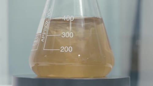 Beige Liquid Swirling in Scientific Conical Flask