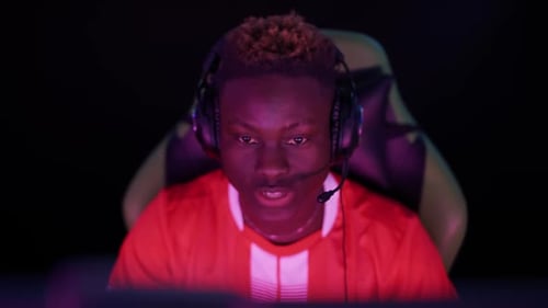 Intense Young Adult Gamer Focused in Dark Room