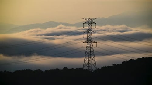 A high voltage tower and a sea of raging, tumbling clouds on a summer morning.