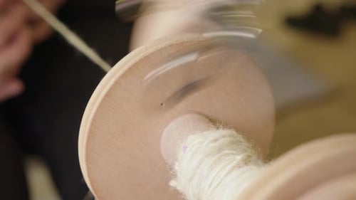 La broche du rouet tourne en gros plan, collecte le fil fraîchement filé, fait du bricolage