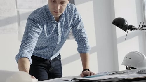 Man Working on Architectural Plans at Desk