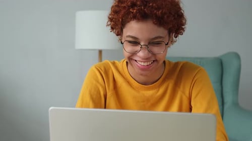 African American Girl Smiling Using Laptop at Home Office Looking at Screen Typing Chatting Writing