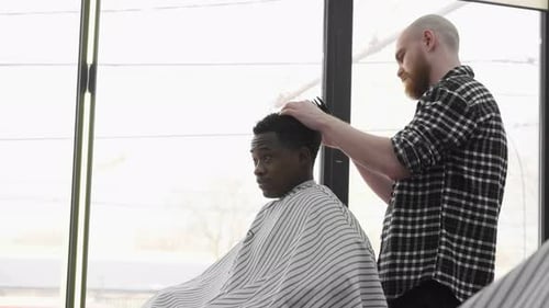 Barber Cutting Young Adult Hair in Barbershop