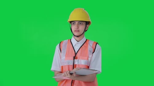 Confused Indian female architect taking notes in building Green screen