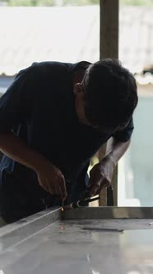 Young Asian Man Welding Two Metals Together and Smiling to the Camera FHD Vertical Video