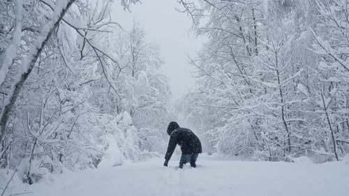 Mann wirft Schnee inmitten schneebedeckter Bäume