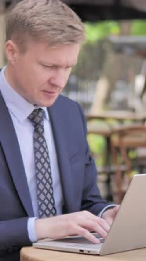 Man in Suit Typing on Laptop Expressing Frustration