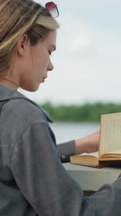 Young Woman Reading Book Outdoors in City Park