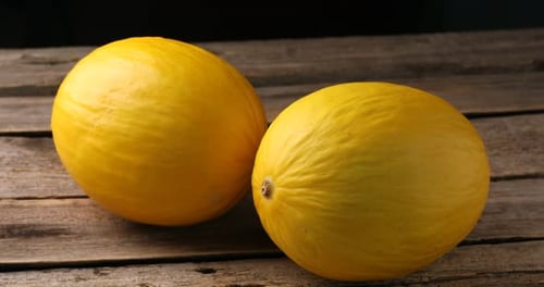 Ganze reife Melonen auf Holztisch, Nahaufnahme. Kamera bewegt sich nach links
