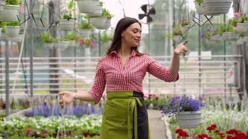 Woman tending to plants in lush tropical greenhouse