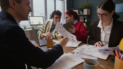 Colleagues Coworking during Business Papers Discussion at Desk in Office