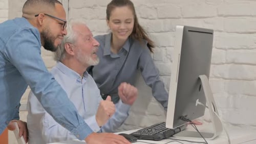 Three People Laughing Together at a Desktop Computer