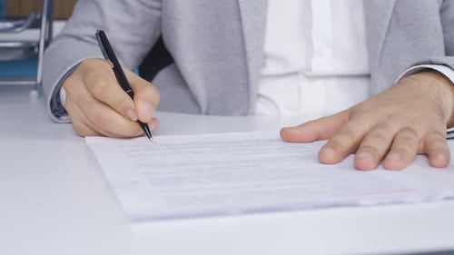 Junger Geschäftsmann unterschreibt Papierkram, nachdem er die Informationen überprüft hat. Vertrag, Vereinbarung.