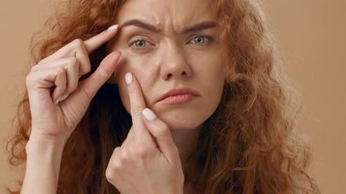 Une femme inquiète examine sa peau sous un éclairage chaud pendant les soins personnels
