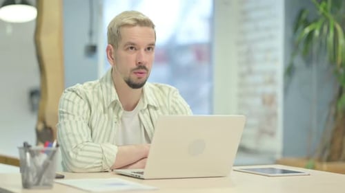 Young Adult Works on Laptop at Office Desk